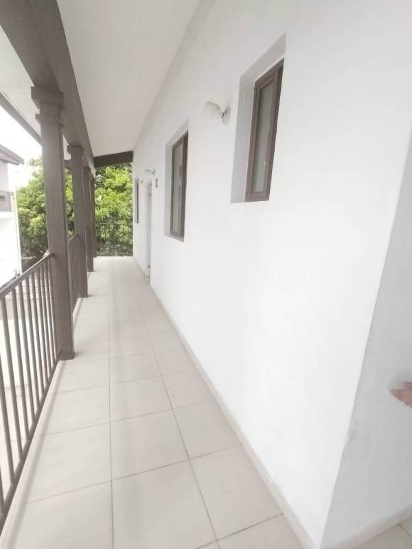 Long covered balcony with tiled floor, white walls, and brown trim windows in Ciudad Radial Juan Díaz