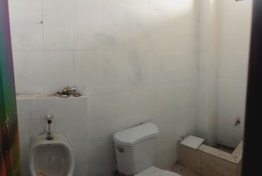 Commercial restroom with white tiles, urinal and toilet at PH Vista Alegre Arraiján Panama