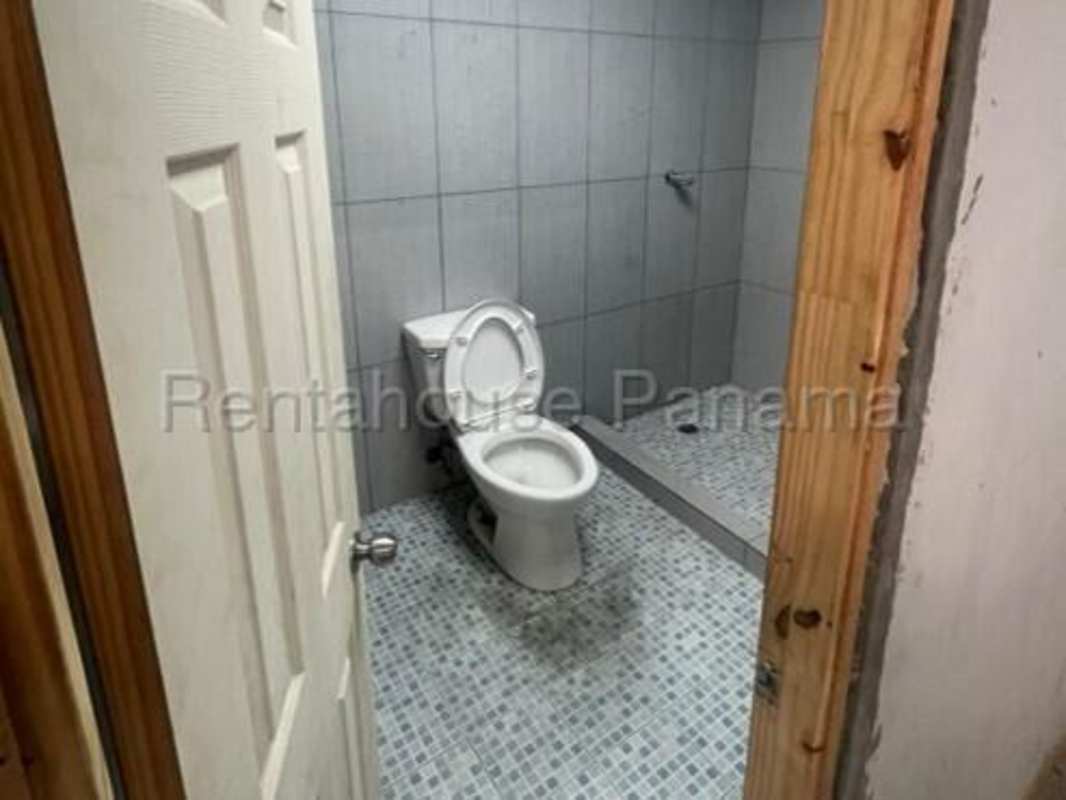 Industrial basic bathroom in warehouse with tiled walls, toilet and shower area La Loceria Panama