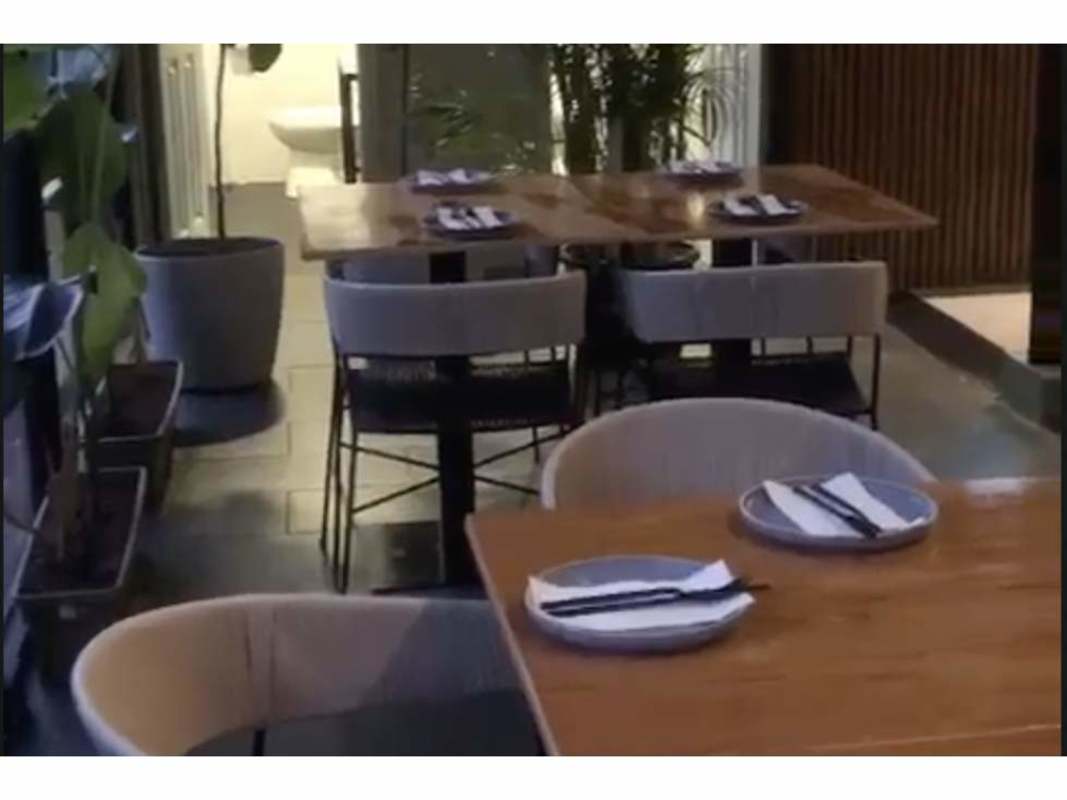 Wood tables upholstered chairs potted plants in minimalist commercial restaurant Panama
