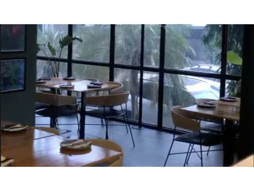 Dining room with large windows, green plants, wood tables commercial rental Panama City