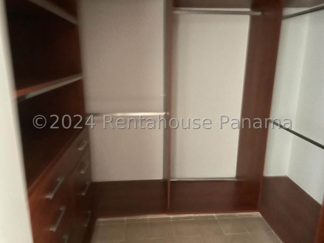 Spacious custom walk-in closet with wood shelving and tiled floor in Casco Viejo Panama City penthouse