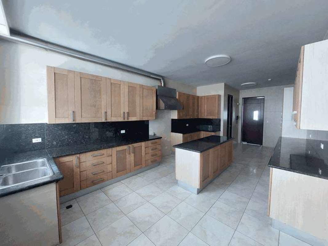 Large kitchen with granite counters, wood cabinetry, island, and stainless appliances in PH AquaMare Punta Pacifica Panama City