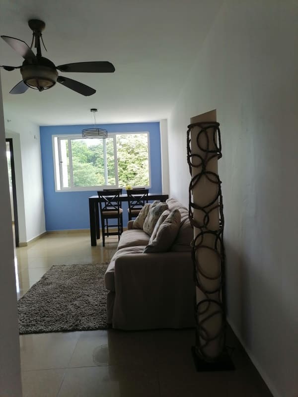 Modern living room with blue feature wall, beige sofa, window view in PH Urbis Tumba Muerto Panama apartment