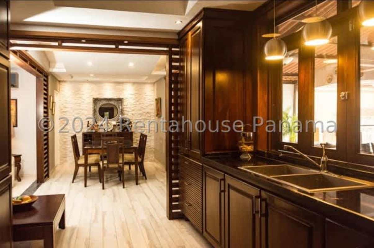 Modern kitchen with granite countertops and wooden cabinets open to dining area Brisas del Golf Panama