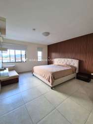 Bedroom with TV, wood accent wall, tile floor PH Midrise apartment Panama Pacifico