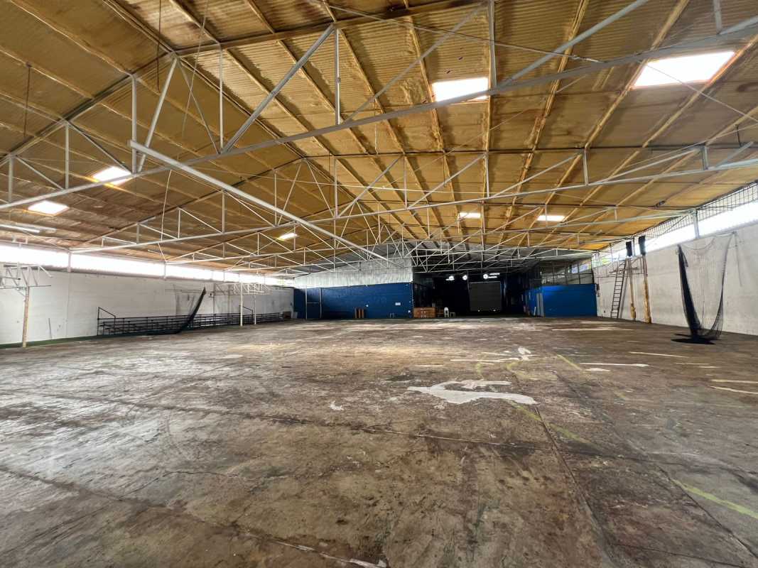 Expansive interior warehouse with concrete floor, metal trusses, and spectator seating in Panama