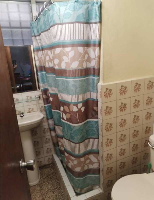 Vintage tiled bathroom with pedestal sink, walk-in shower and frosted window in Carrasquilla Panama