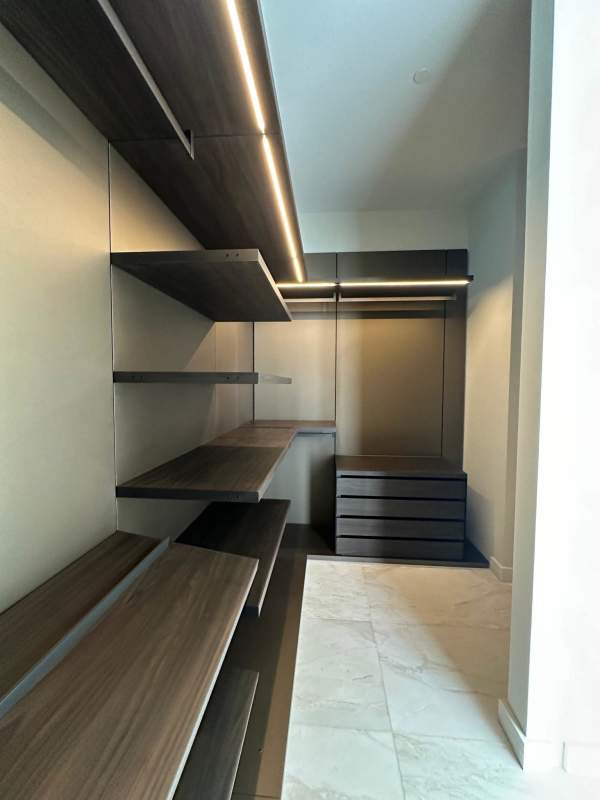 Custom-designed dark wood closet with LED lighting, marble flooring at La Maison by Fendi Panama