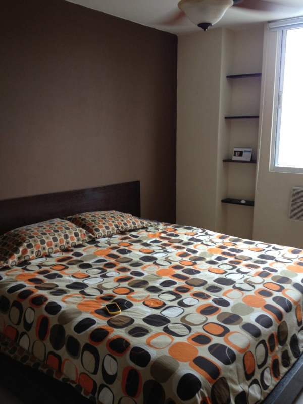 Bedroom with geometric bedding, accent wall, window and shelving at PH Onyx Panama