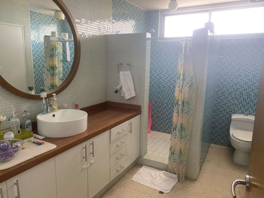 Bathroom with blue mosaic tiles, vessel sink, round mirror PH Las Llamas