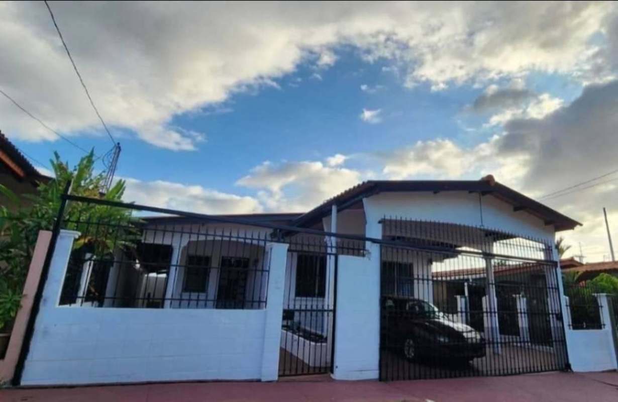 Front exterior of a single-story fenced house with covered parking in Brisas del Golf Panama for rent