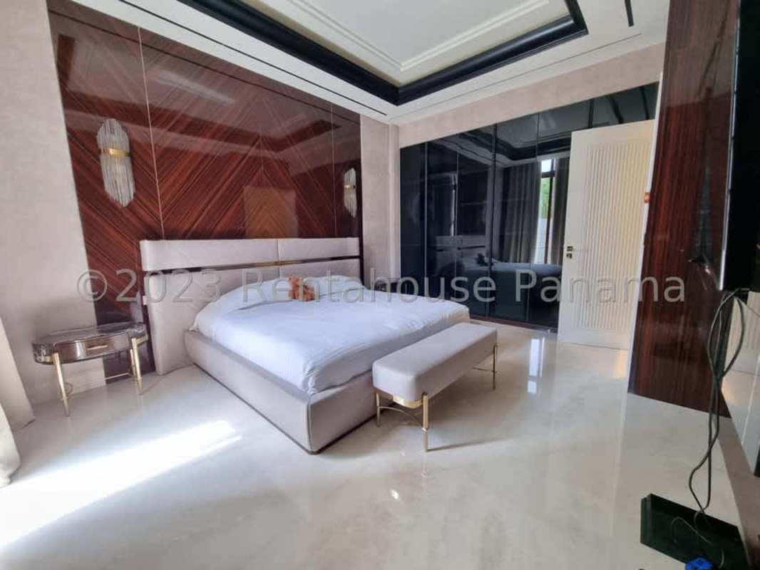 Luxury bedroom with wood accent wall, glossy wardrobes, and marble floors in Ocean Reef Panama