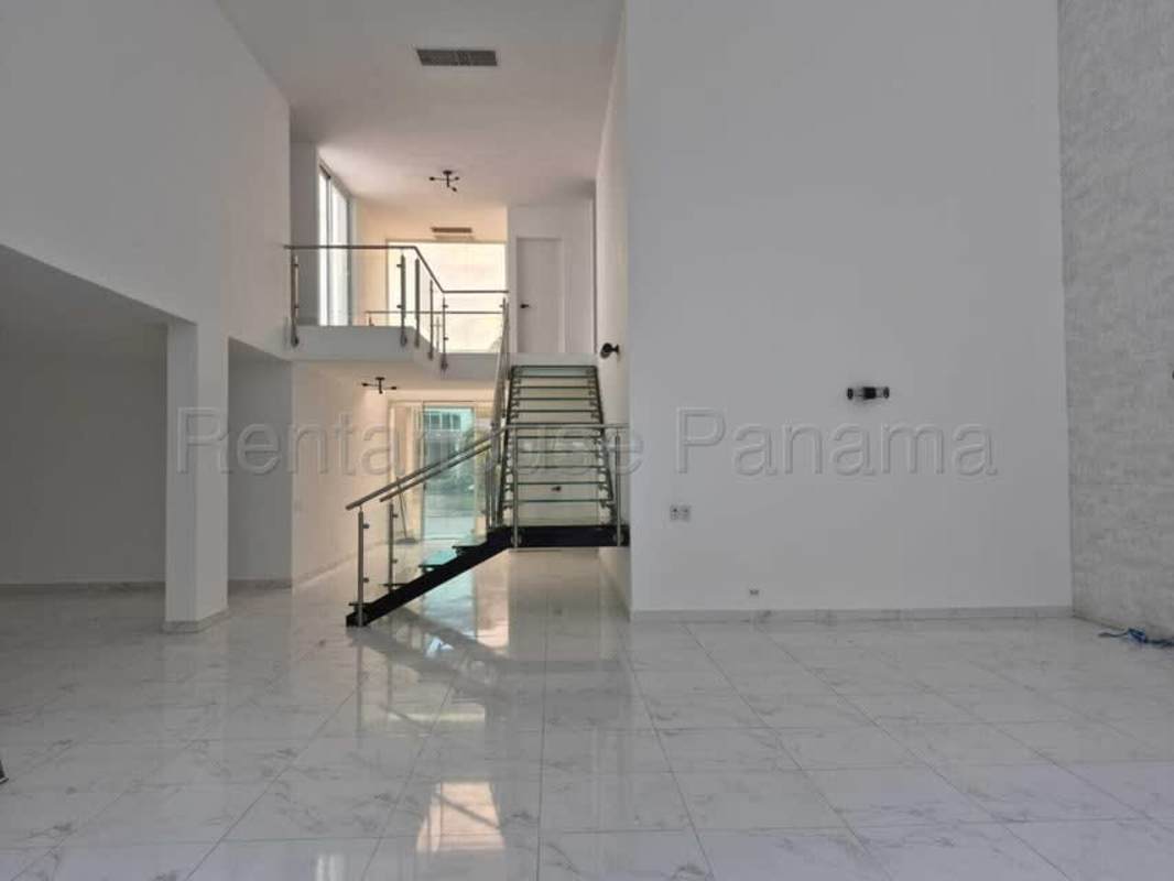 Spacious living area with marble floors, double-height ceiling and glass staircase in Costa Sur Panama home