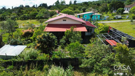 Aerial shot showing fenced garden, red roof house, countryside and mountain backdrop Boquete Panama