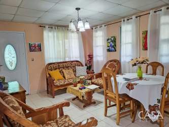 Bright living and dining room with wooden sofas and round dining table in Volcancito Boquete house Panama