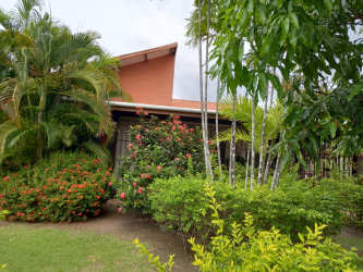 Front garden view of country home for sale San José with vibrant landscaping and flowers