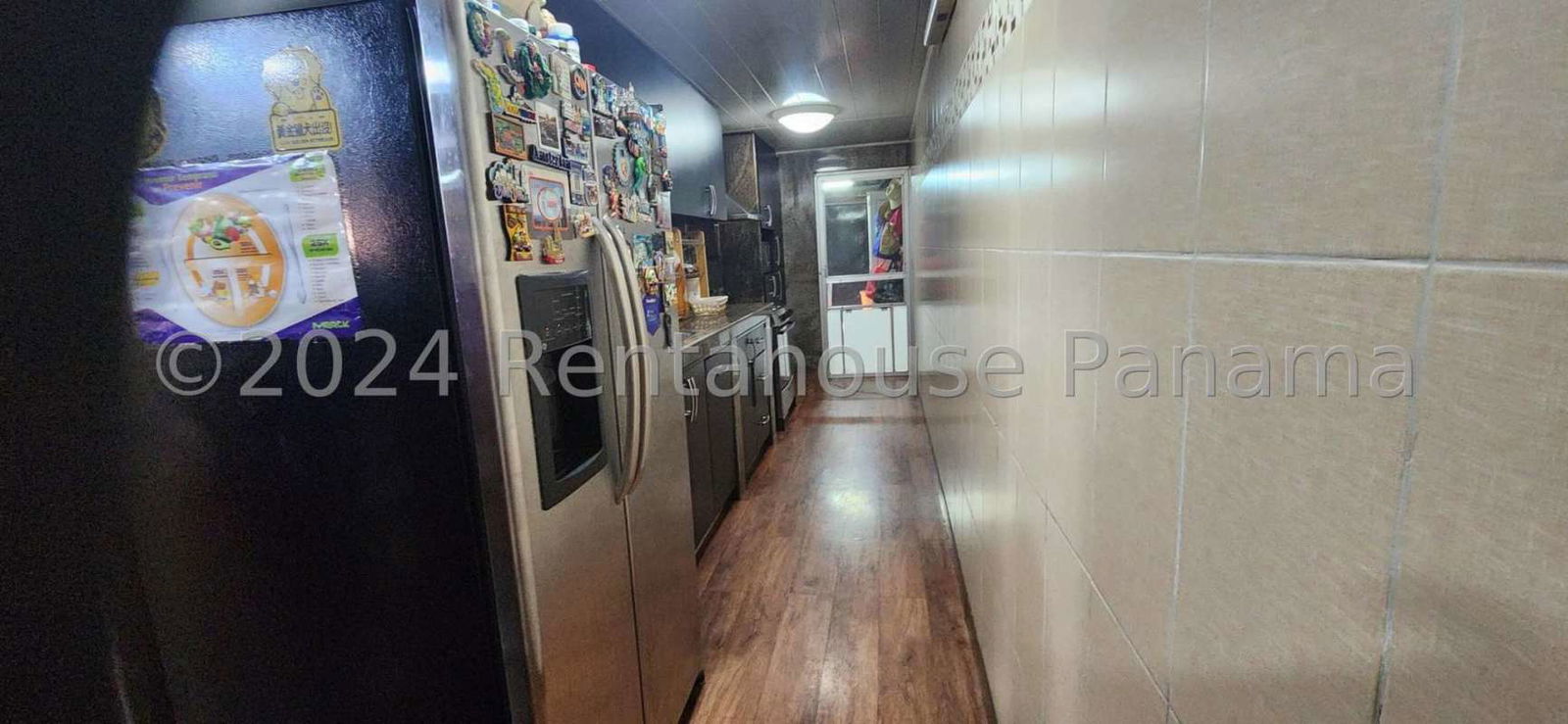 Narrow kitchen with refrigerator, microwave, stove and upper cabinets Panama