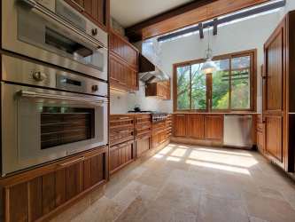 Gourmet kitchen with wooden cabinetry, stainless appliances, and large windows in mountain estate El Valle