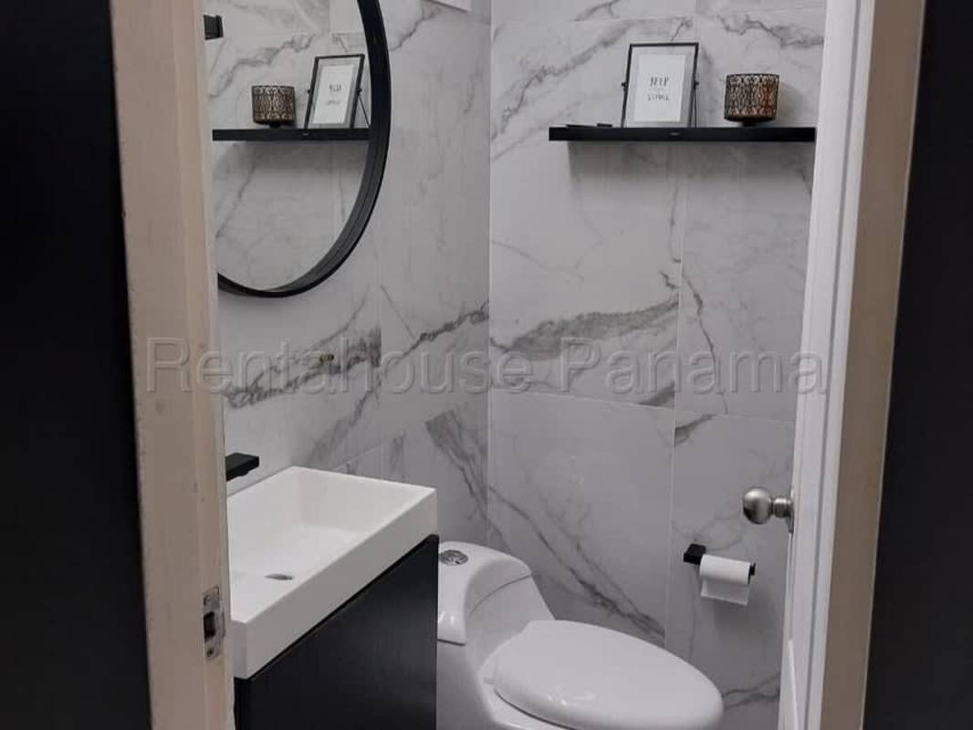 Small modern bathroom with marble look tiles, round mirror and compact vanity in PH Paseo Real Panama