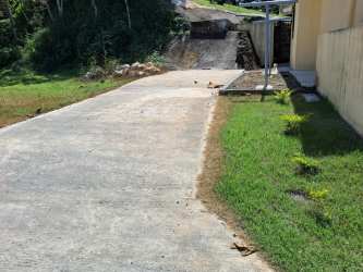 Concrete driveway with carport next to green lawn in Puerto Pilón rental home Panama