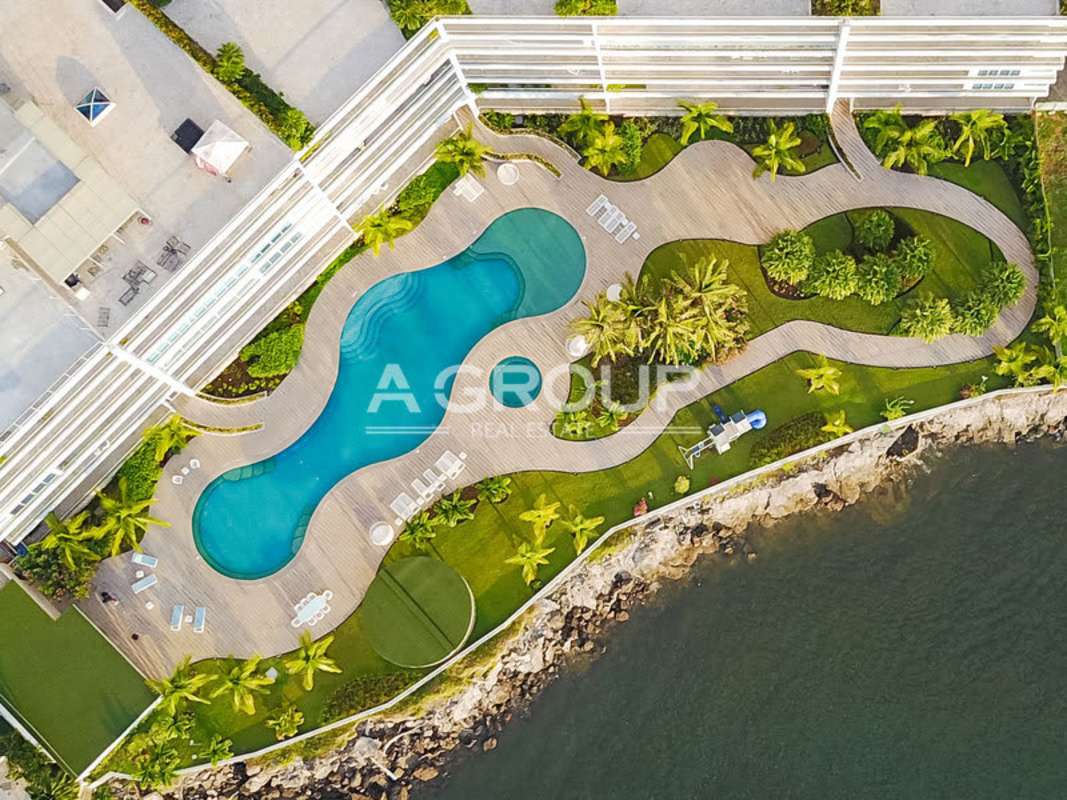 Poolside lounge with palm trees and waterfront view at Miradores at The Point Panama City