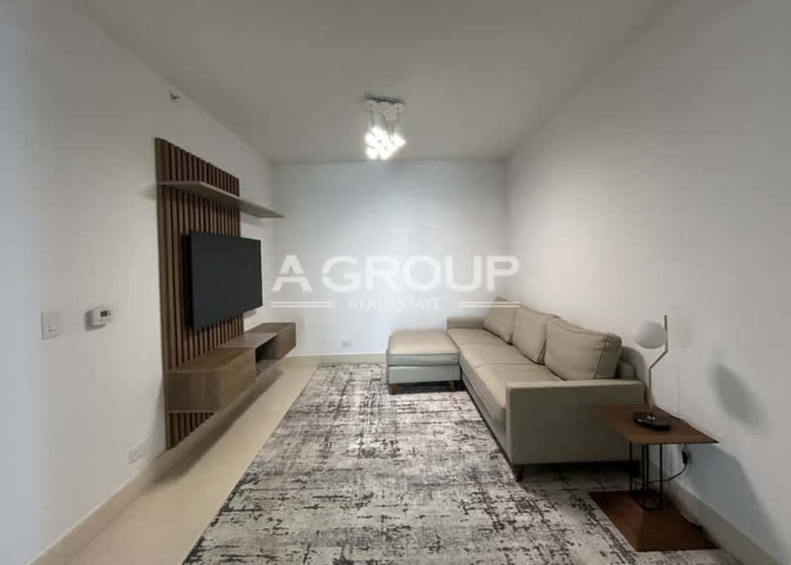 Modern minimalist living room featuring L-shaped sofa and wood accent wall in The Point Punta Paitilla