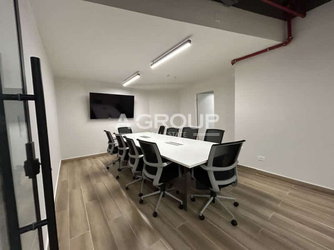 Minimalist office conference room with white table wall-mounted TV wood-inspired flooring in Financial Park Tower Panama City
