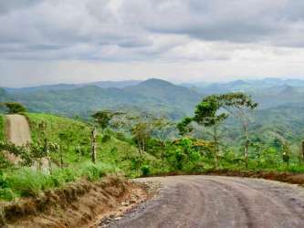 Dirt road through rolling green landscape toward mountains near El Valle Panama