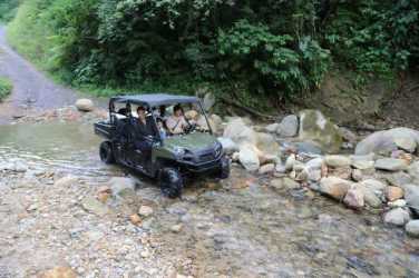 4x4 vehicle crossing shallow rocky stream through forest on rural land near El Valle de Antón