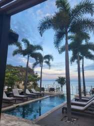 Infinity pool with lounge chairs overlooking ocean and palm trees Punta Caelo beachfront community Panama