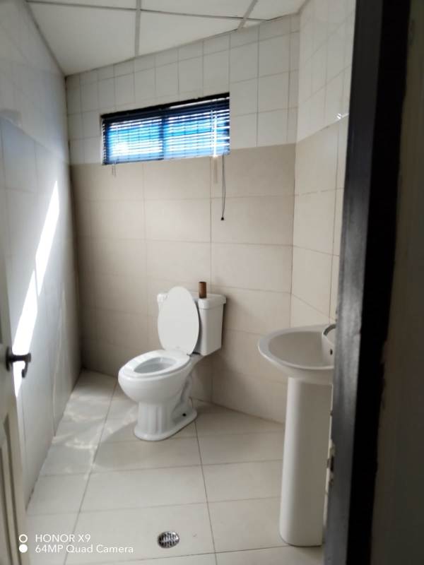 Simple bathroom with pedestal sink and tiled walls in commercial warehouse Panama