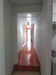 Narrow hallway with white walls and red tiled floor in La Chorrera apartment