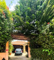 Gated driveway surrounded by lush gardens, covered garage of Alto Boquete house for sale