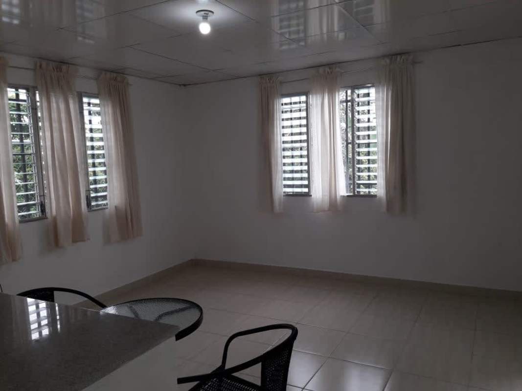 Minimalist bright living room with glass table, black chairs, and multiple windows Villa Serena Panama