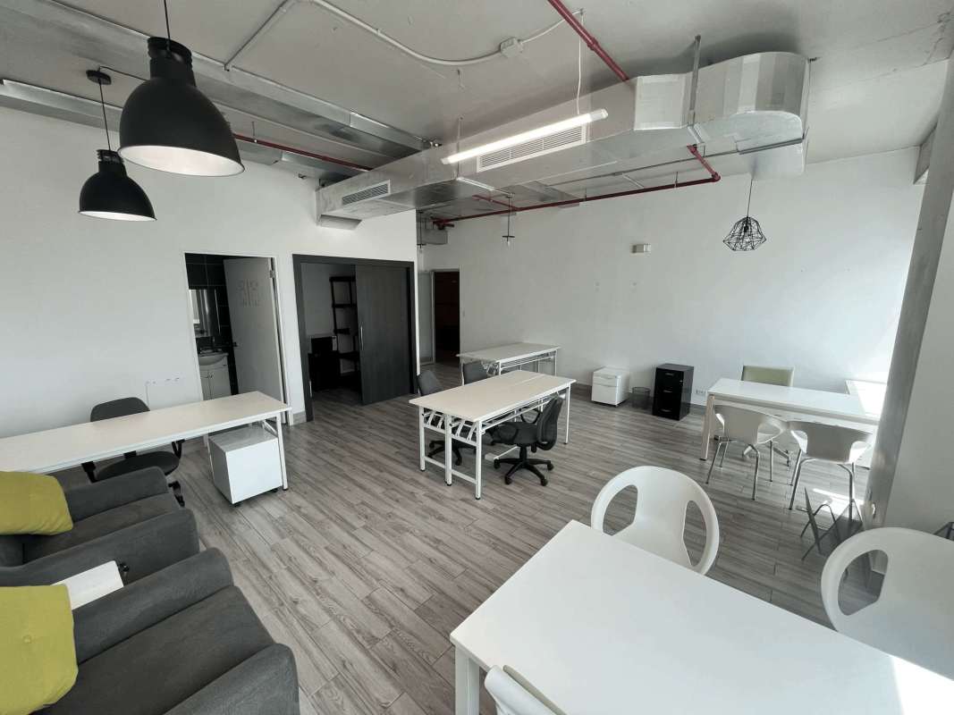 Industrial style open office floor with exposed ducts and pendant lights at Office 77 Panama City