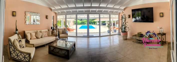 Tropical style living room with tile floors, sliding glass doors to pool, ceiling beams Costa Blanca Villa Panama