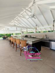 Outdoor kitchen with bar seating and grill, vaulted white ceiling, garden views Costa Blanca Panama