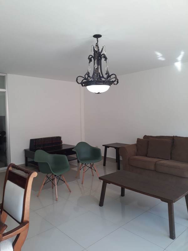 Living room with brown sofa chandelier green chairs tiled floors at Altavista Residences El Bosque