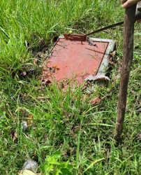 Closeup utility cover in grass with metal tool Ollas Abajo farm Panama