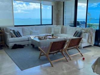 Bright living room with floor-to-ceiling windows and Pacific ocean view at Royal Palm Gorgona apartment
