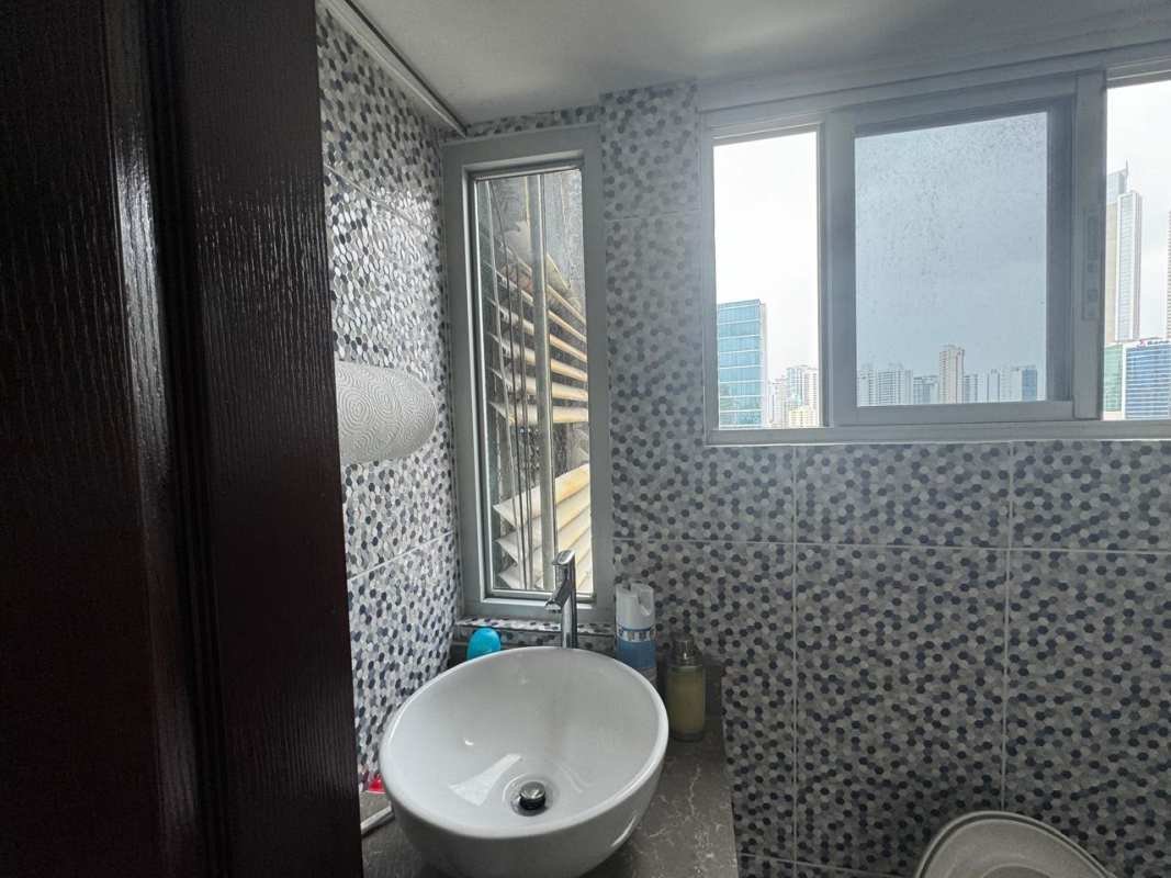 Modern bathroom with vessel sink and mosaic tiles overlooking cityscape in Obarrio Business Tower
