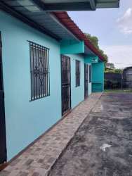 Simple light blue house with red roof security bars on windows and driveway in Vacamonte Panama