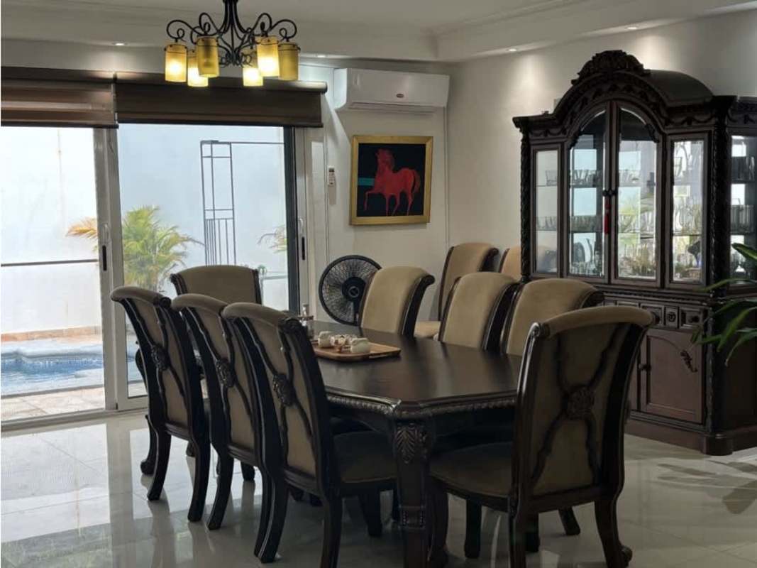Large dining table with upholstered chairs and sliding doors to pool in family house Altos del Golf