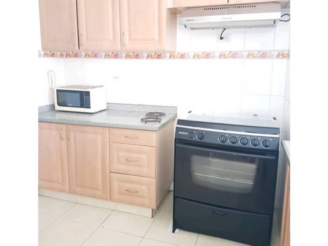 Apartment kitchen with wooden cabinets gas stove microwave tile backsplash in PH Pacific Blue Panama City