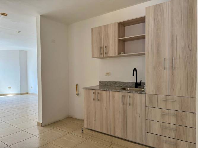 Small kitchen with granite countertop and light wood cabinetry Panama apartment