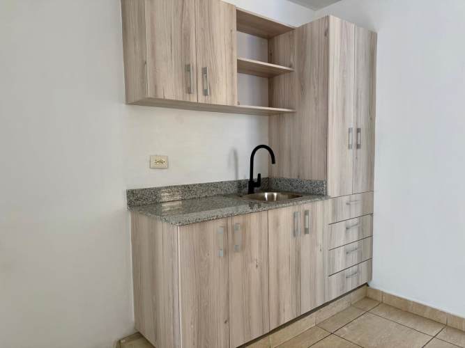 Minimalist kitchen with light wood cabinets, granite countertops in Panama City apartment