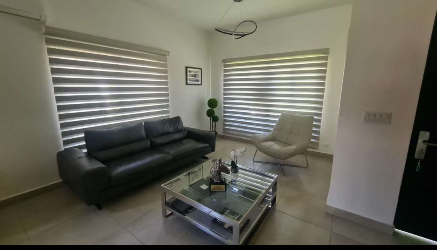 Stylish living room with natural light, black sofa, and beige accents in luxury Embassy Club house Panama