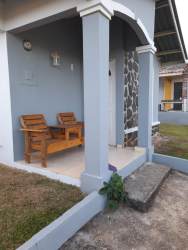 Covered porch wooden bench decorative columns stone accent single family house Quinta del Pacifico La Chorrera Panama