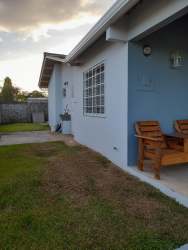 Covered porch with wooden chairs stone accent wall and decorative columns in Quinta del Pacifico La Chorrera Panama